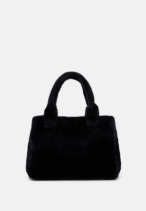 Sac à main en fausse fourrure noire douce avec poignées doubles arrondies et corps rectangulaire sur fond gris clair uni.