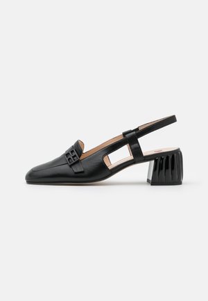 Chaussure slingback en cuir noir avec talon bloc, bout carré et détail décoratif de boucle sur la partie supérieure.