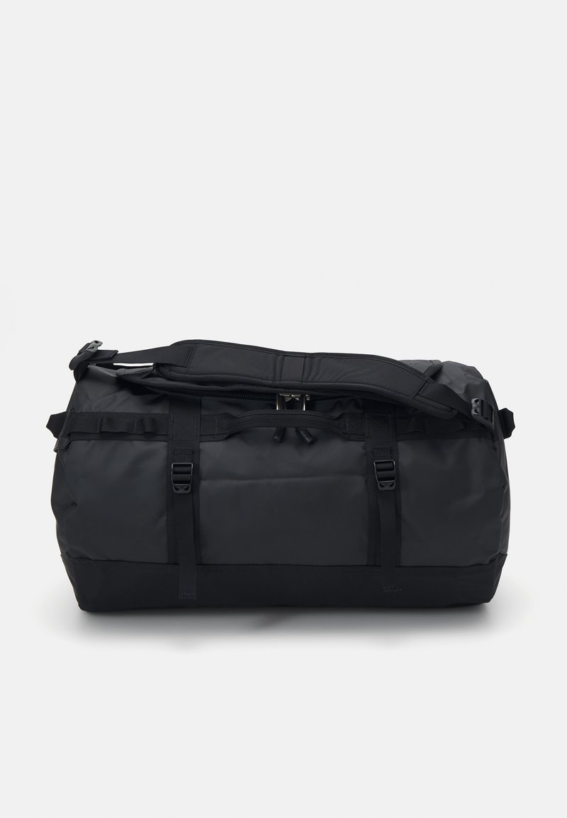 Sac de sport noir en matière durable, de forme arrondie, avec des bretelles ajustables, des boucles et un design minimaliste.