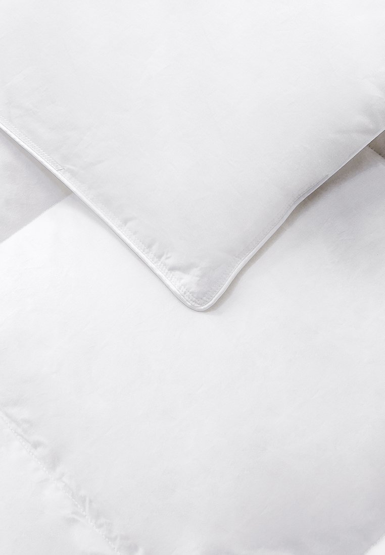 Set di biancheria da letto bianca che include un cuscino e un piumone, caratterizzato da una texture liscia e linee pulite, con una cucitura discreta lungo i bordi.