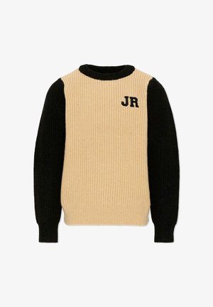 Beige gebreide trui met zwarte lange mouwen en kraag, met zwarte "JR" letters geborduurd op de bovenste linker borst.