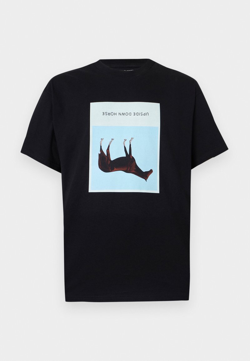 Schwarzes T-Shirt mit einer zentrierten, auf dem Kopf stehenden braunen Pferdeillustration auf einem blauen Quadrat und dem Text „UPSIDE DOWN HORSE“ darüber.