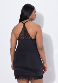 Abito lungo in satin nero con bordo in pizzo all'orlo e un delicato design in pizzo sulla schiena. Spalline regolabili per una vestibilità personalizzabile.