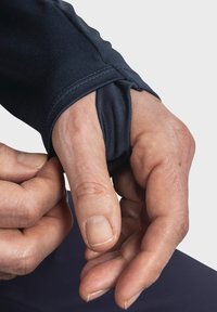 Navyfarbendes Langarmhemd mit Daumenloch, aus dehnbarem Material. Nahaufnahme einer Hand, die den Manschettenaufschlag anpasst, wobei die glatte Textur und die Nähte sichtbar sind.