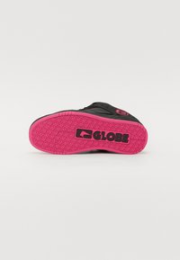 Crna potplatica skate cipela s ružičastom gumiranom vanjskom podlogom, s teksturiranim uzorkom i istaknutim 'GLOBE' logom.