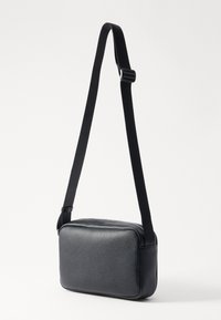 Schwarze Leder-Crossbody-Tasche mit rechteckiger Form, strukturierter Oberfläche und verstellbarem Trageriemen. Verfügt über einen Reißverschluss und ein minimalistisches Design.