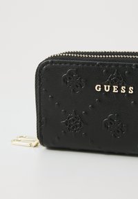 Zwarte faux leren portemonnee met reliëf bloemenpatronen, hardware in goudkleur en een ritssluiting met contraststiksel.