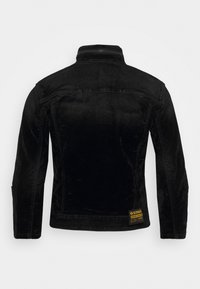 Black corduroy jacket with a high collar, long sleeves, and a G-Star logo patch at the bottom. Smooth texture with a fitted design.