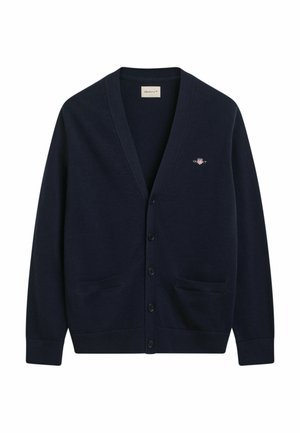 Navy vest met V-hals, zes knopen, twee voorzakken en een klein logo detail. Gemaakt van zacht gebreid materiaal met een gestructureerde afwerking.