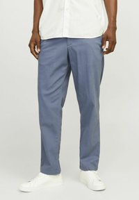 Pantalones azul claro con un corte relajado, confeccionados en una tela suave, cuentan con bolsillos laterales y se combinan con zapatillas blancas.