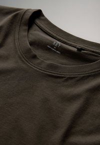 Donkergroen katoenen t-shirt met een ronde hals, voorzien van een label met de tekst "SET" en "MADE IN BANGLADESH" in de kraag.