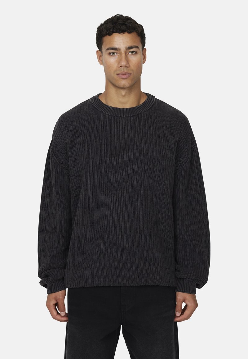 Maglione a coste grigio scuro con scollo rotondo, spalle scese e maniche lunghe, abbinato a pantaloni neri.