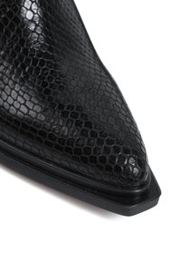 Czarne botki za kostkę z teksturowanej skóry, z ostrym noskiem i gładką czarną podeszwą. Wierzch ma wzór przypominający skórę węża.