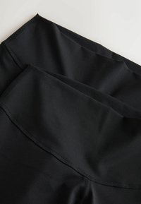 Czarne legginsy sportowe z gładkiego, elastycznego materiału, z wysokim stanem i płaskimi szwami dla komfortu i elastyczności.