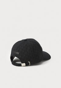 Black cap featuring a textured fabric with a geometric pattern, adjustable strap with silver hardware at the back, and curved brim.