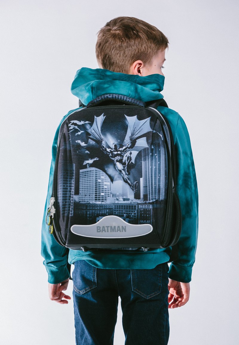 Schwarzer Batman-Rucksack mit einem Design der Stadtsilhouette und einem großen Batman-Logo. Glatte Textur, Reißverschlussfüllungen und graue Akzente.