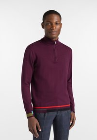 Lila, langärmliger Reißverschluss-Pullover mit geripptem Kragen und farbigen Streifenakzenten in Rot, Grün und Blau am Saum und an den Bündchen.