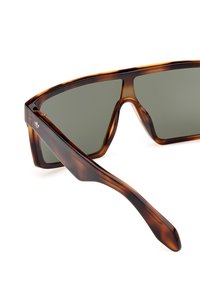 Brown tortoiseshell sunglasses with a geometric frame, gray lenses, and a smooth texture. Features subtle branding on the temple.