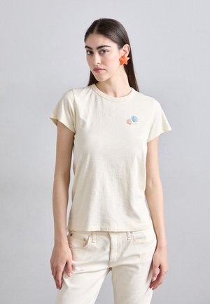 Camiseta de algodón crema con mangas cortas, que presenta un pequeño gráfico de concha azul y coral en el pecho. Textura suave y corte relajado.