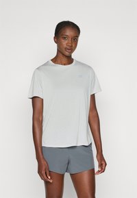 T-shirt athletic court à manches courtes de couleur gris clair avec un tissu texturé et un logo discret sur la poitrine. Associé à un short gris foncé.
