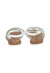 Weiße Sandalen mit dekorativen Riemen, die mit silbernen Akzenten versehen sind, einer flachen Sohle und einer gepolsterten braunen Innensohle für mehr Komfort.