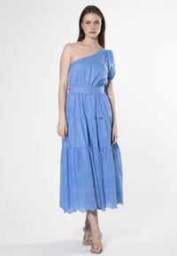 Eén-schouder blauwe jurk met pofmouw, ceintuur in de taille en een gelaagde rok met geborduurde bloemaccenten langs de zoom. Zacht katoen materiaal.