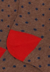 Calze marroni con pois blu navy e sezione del tallone di un vivace rosso, che mostrano texture a maglia e dettagli in primo piano.