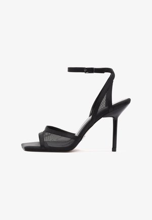 Schwarze Sandalette mit hohem Absatz, dünnem Knöchelriemen, quadratischer offener Zehenpartie und Netzpaneelen an den Seiten, von der Außenseite gezeigt.
