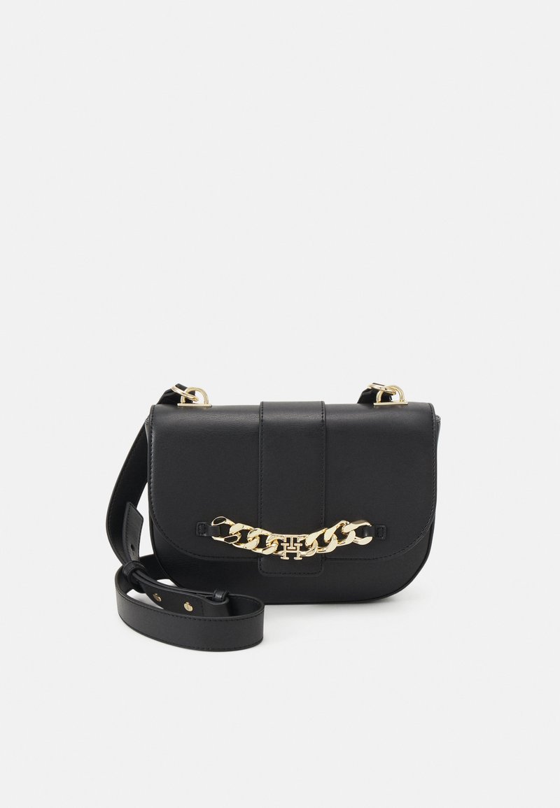 Borsa a spalla in pelle nera con un accento in catena dorata, forma quadrata, chiusura a pattina e tracolla regolabile. Texture liscia e design minimale.