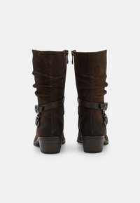 Braune Wildlederschaftstiefel mit einem lässigen Design, Lederbändern und metallischen Schnallen. Die Stiefel verfügen über einen gestapelten Absatz und auffällige Nähte.