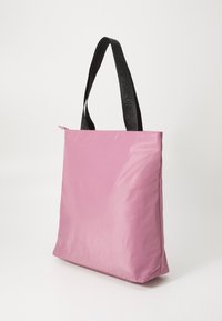 Rosa nylon tote bag med flatt design, med svarte, pregete håndtak. Glidelås på toppen og glatt, skinnende tekstur.