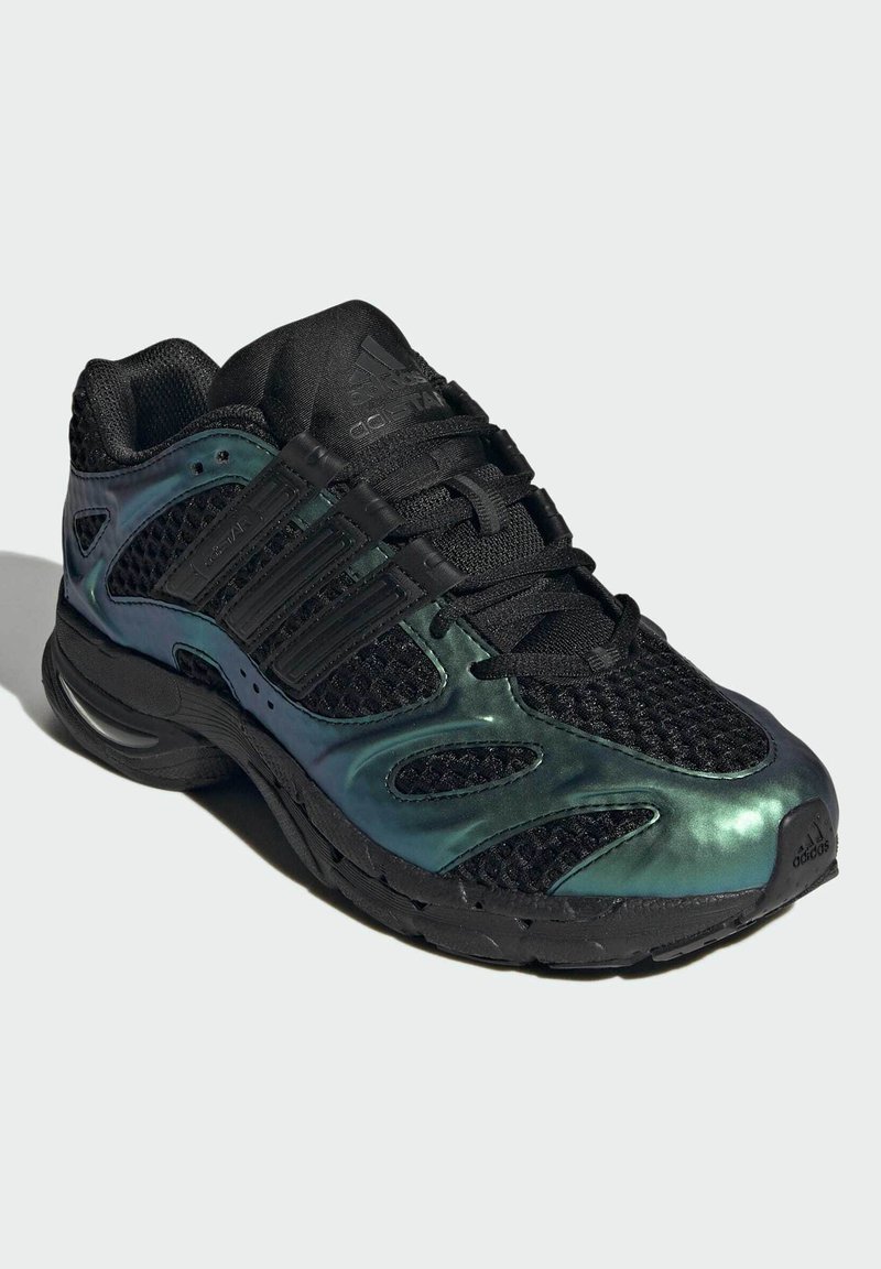 Sort og iriserende grøn Adidas sneaker med mesh overdel, polstret sål og snørelukning vinklet for at vise front- og sidedetaljer.