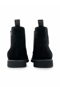 Zwarte suède enkellaarsjes met een ronde neus, elastische zijkanten en een vlakke rubberen zool. Voorzien van een treklip aan de achterkant voor eenvoudig aan- en uittrekken.