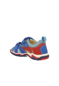 Kindersportshoe met blauwe, rode en grijze stof, verstelbare band, rubberen zool en uitsparingen voor ventilatie.