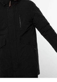 Mustavilla eristetty takki, jossa on vetoketjullinen rintatasku, napilla kiinnitettävät sivutaskut ja kiristettävä huppu. Ominaisuuksia teksturoitu kangas.