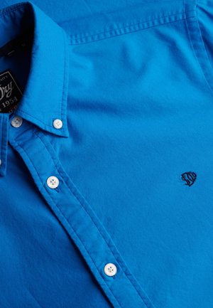 Blauwe overhemden gemaakt van katoen, met een klassieke kraag, witte knopen en een klein logo geborduurd aan de linkerkant.