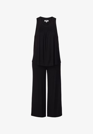 Haut noir sans manches plissé avec pantalon à jambes larges, étiquette DKNY visible au niveau du col.