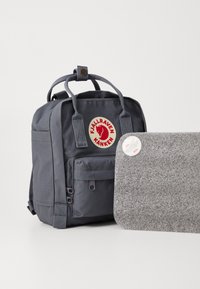 Sivi Fjällräven Kånken ruksak s logotipom, platnenim ručkama i prednjim džepom. Uz njega ide sivi filcani pokrov za laptop s zaobljenim rubovima.