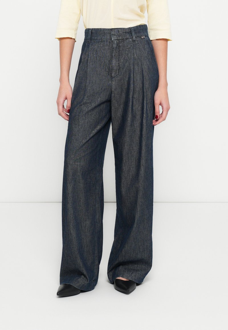 Széles szárú, sötét farmernadrág magas derékrésszel és elöl, redőzött kialakítással. Texturált felülettel és vasalt hajtással a lábszár mentén.