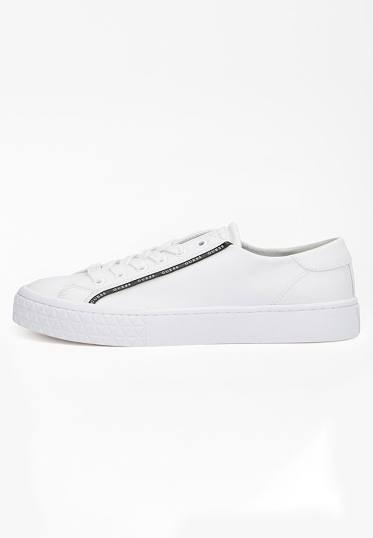 Sneaker bianchi a basso profilo con design stringato, suola testurizzata e striscia nera con il logo "GUESS" ripetuto lungo il lato.