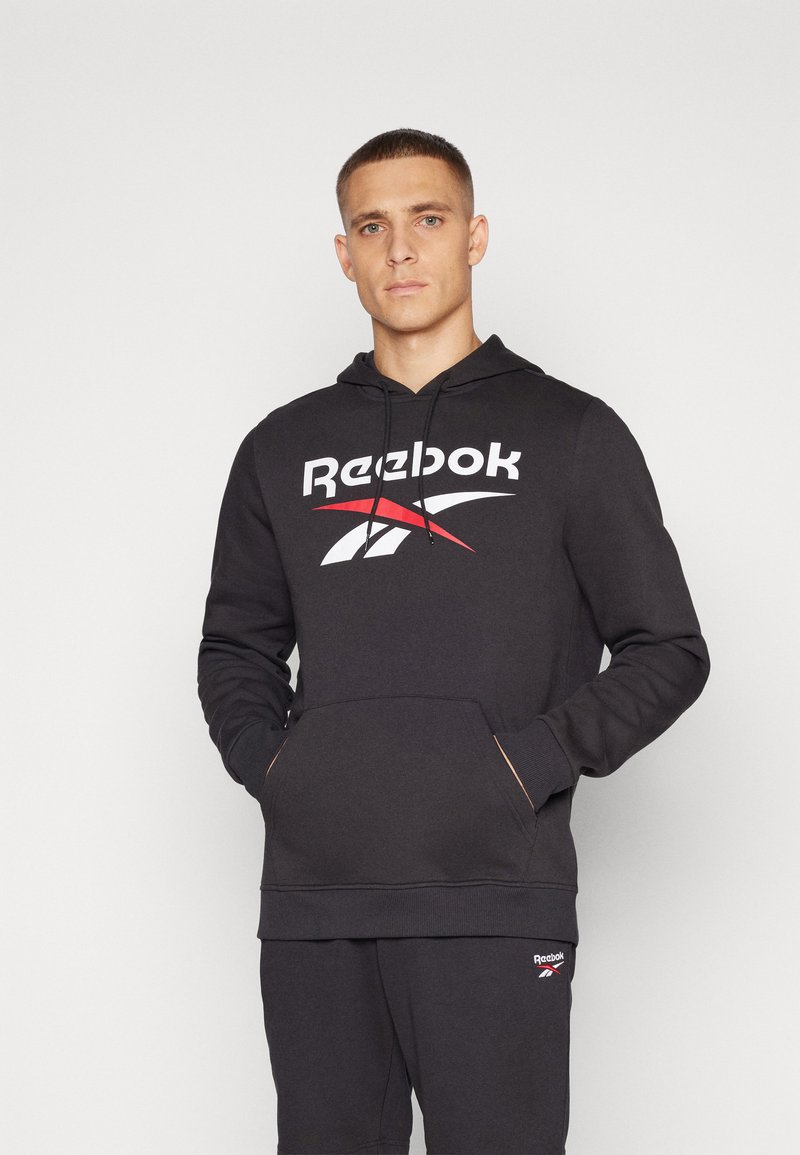 Fekete kapucnis sweatshirt fehér és piros Reebok logóval. Elől zseb található, valamint bordázott mandzsetták. Lágy anyag, laza kialakítás.