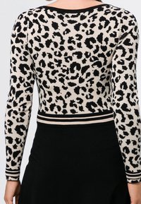 Leopardmönstrad långärmad topp i beige och svart, med randig nederkant. Stickad material, figurnära design, rund halsringning och kontrasterande detaljer.