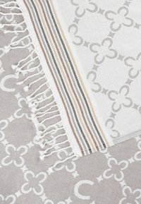 Katoenen blend dekentje met een geometrisch patroon in grijs en wit, met franjes aan de randen en gestreepte accenten in beige en zwart.