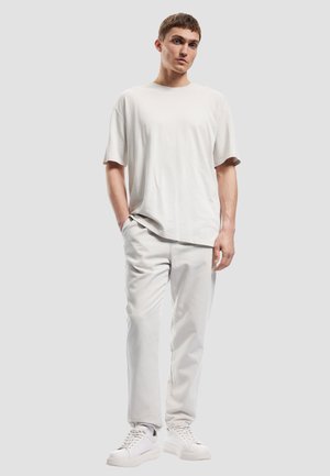Light grey oversized t-shirt and matching trousers, both in a soft fabric, paired with white sneakers. Simple design, relaxed fit.