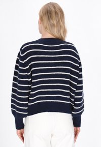 Granatowy krótki sweter z białymi poziomymi paskami, żebrowana faktura i okrągły dekolt. Posiada opadające ramiona i długie rękawy.