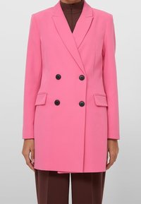 Dubbelzijdig blazer in felroze, gemaakt van een gladde stof. Voorzien van zwarte knopen, ingesneden revers en zijzakken.