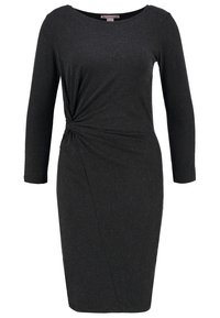 Schwarzes Kleid aus weichem Stoff, mit rundem Ausschnitt, langen Ärmeln und einem verdrehten Knoten-Detail an der Taille, mit einer figurbetonten Silhouette.