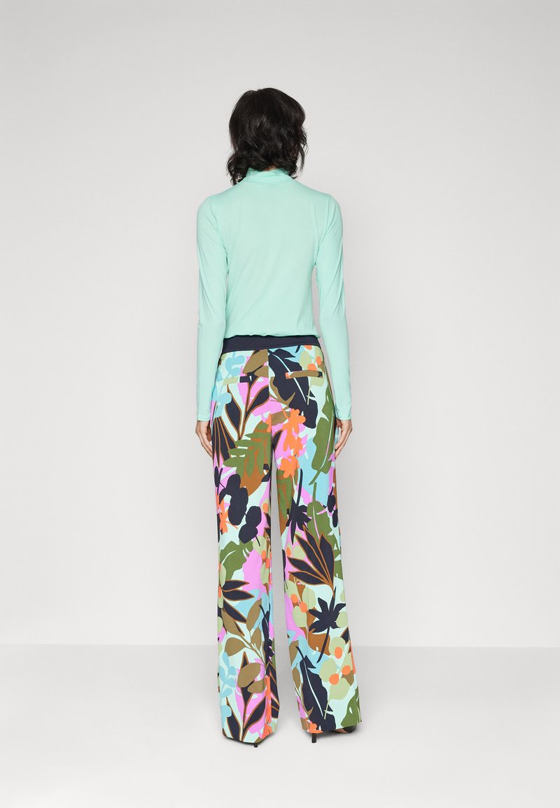 Jasnoniebieska bluzka z długim rękawem i stójką, w zestawie z szerokimi spodniami w kolorowy kwiatowy wzór. Gładki materiał z kontrastowym pasem.