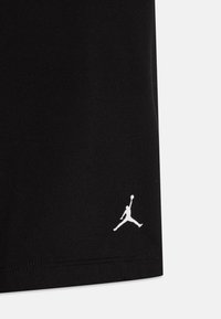 Melni sporta šorti, kas izgatavoti no mīksta auduma, ar baltu Jumpman logo pie apakšmalas. Vienkāršs dizains bez papildu rakstiem vai akcentiem.