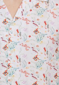 Camisa de manga corta y cuello en tela ligera con un patrón floral y de vida marina, en colores vibrantes que incluyen rojo, azul, verde y amarillo.